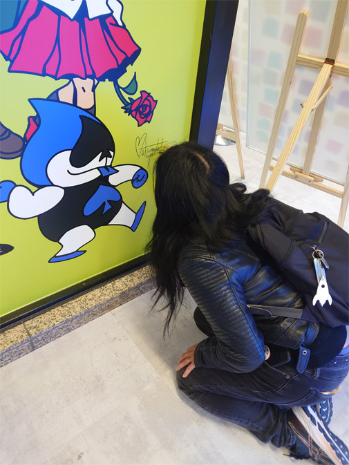 A photo of me crouched down, signing the mural with my signature