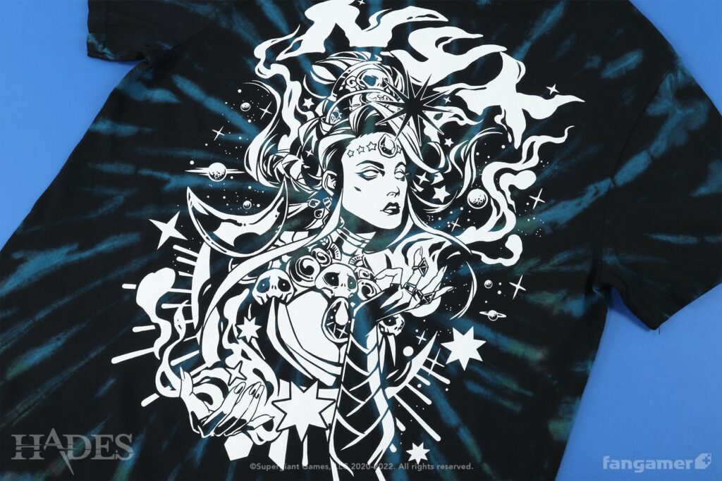 A psychadelic-looking drawing of the goddess of the night, stars and planets and swirls surrounding her in a mystical manner. Smoky lettering at the top reads "Nyx". Printed on a black, blue, and green tie-dye shirt